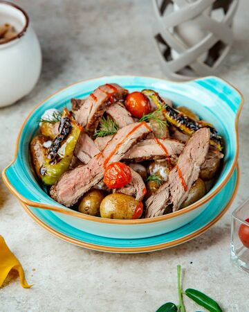 oven-baked meat and potatoes with tomatoes and peppersの写真素材