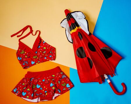 red split swimsuit for girls and red polka dot umbrellaの写真素材