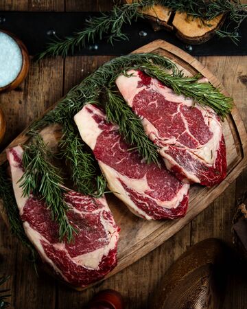fresh rib eye steaks on wooden boardの写真素材
