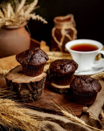 three chocolate muffins served in rustic style on wooden boardsの写真素材