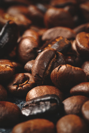 close up view of brown coffee seeds on dark surface textured grainの写真素材