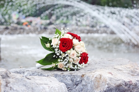 The beautiful beige bouquet of the bride lays on a fountain parapetの写真素材