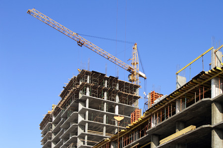 Building cranes and under construction building against the clear sky