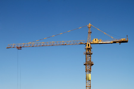 The building tower crane against the blue sky