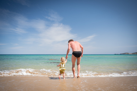 Father and little daughter walking on summer beach. Outdoors child activity, active healthy lifestyle,  summer family vacationの写真素材