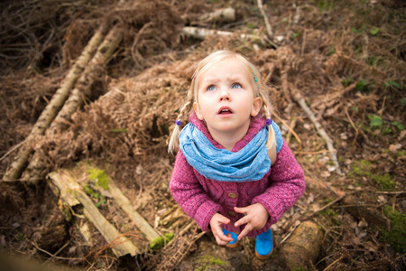 Little girle observing nature in the forest with big  blue eyes and mouth openの写真素材