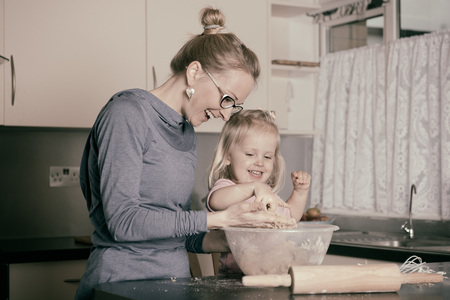 Mother and little toddler daughter having fun whilst baking in the kitchenの写真素材