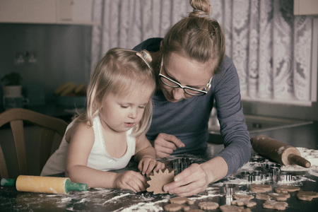 Mother and little toddler daughter having fun whilst baking in the kitchenの写真素材