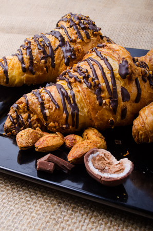 Closeup Croissants on a wooden plate. chocolate and almonds. Focus on Croissant. The background is blurred out of focus at some point.の写真素材