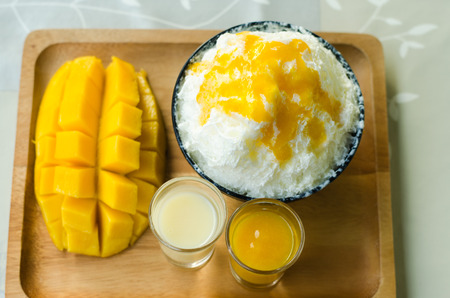 Bingsu ( Korea food) mango served with sweetened condensed milk on tableの写真素材