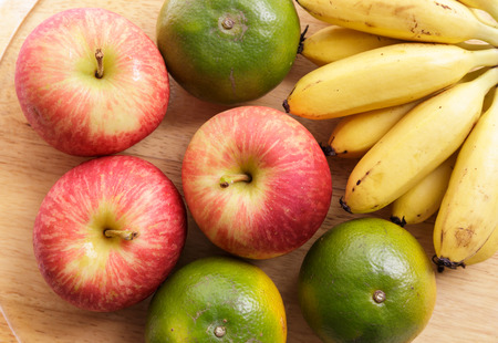 Apple, orange and banana on wood trayの写真素材