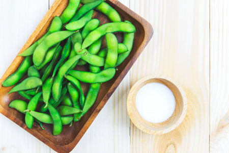 Soya beans pod in wooden plate with salt on wood floorの写真素材