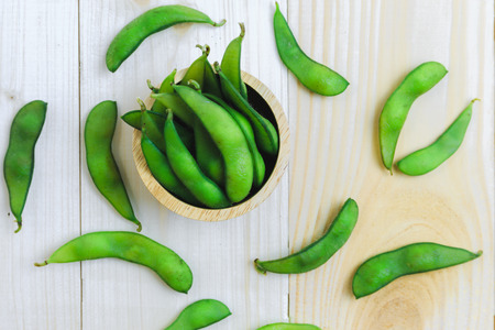 Soya beans pod in wooden bowl on wood floorの写真素材