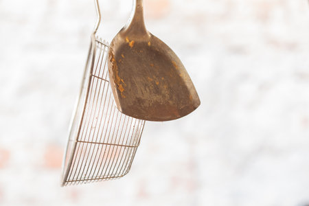 Kitchen utensils hanging outside, ready to be used with grill, rustic iron cooking set, dishwareの写真素材