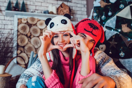 A  beautiful loving couple in funny hats posing in Christmas decorationsの写真素材