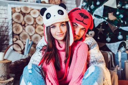 A  beautiful loving couple in funny hats posing in Christmas decorationsの写真素材
