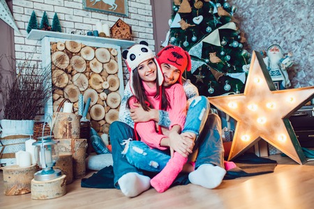 A  beautiful loving couple in funny hats posing in Christmas decorationsの写真素材