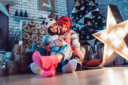 A  beautiful loving couple in funny hats posing in Christmas decorationsの写真素材
