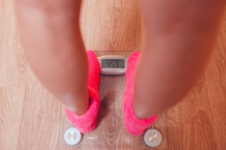 The girl in pink socks standing on weigher. Wood floorの写真素材