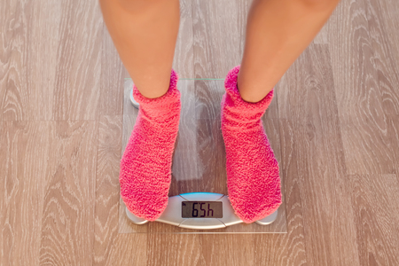 The girl in pink socks standing on weigher. Wood floorの写真素材