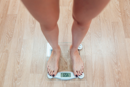 The girl standing on weigher. Wood floorの写真素材