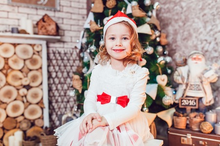 Girl dressed as Santa Claus posing with Christmas decorationsの写真素材