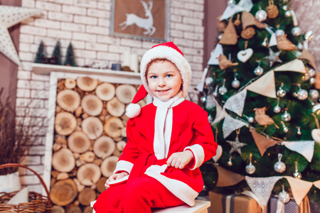Boy dressed as Santa Claus posing with Christmas decorationsの写真素材