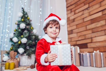 Boy dressed as Santa Claus posing with Christmas decorationsの写真素材
