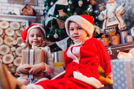 Children dressed as Santa Claus posing with Christmas decorationsの写真素材