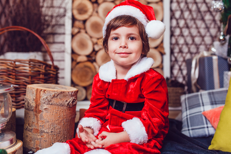 Boy dressed as Santa Claus posing with Christmas decorationsの写真素材