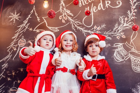 Children dressed as Santa Claus posing with Christmas decorationsの写真素材
