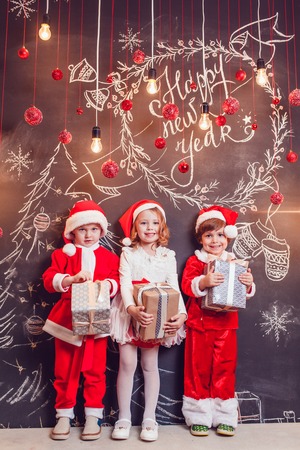Children dressed as Santa Claus posing with Christmas decorationsの写真素材