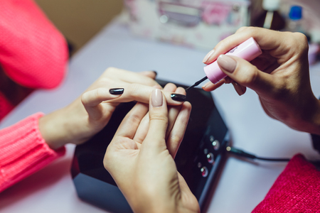 Manicure. Beauty saloon. Close-up.Apply black nail polish.の写真素材