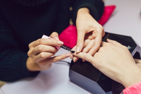 Manicure. Beauty saloon. Close-up.Apply black nail polish.の写真素材