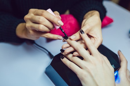Manicure. Beauty saloon. Close-up.Apply black nail polish.の写真素材