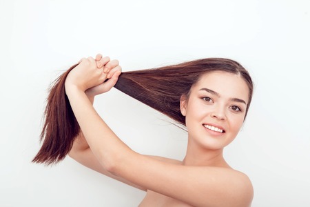 A beautiful Asian girl holds her hair in hands.の写真素材