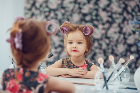 Little girl in hair curlers in a beauty studioの写真素材