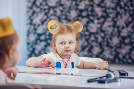 Little girl in front of the mirror doing her makeupの写真素材