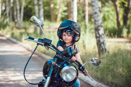 Little beautiful girl in a helmet on a motorcycle.の写真素材