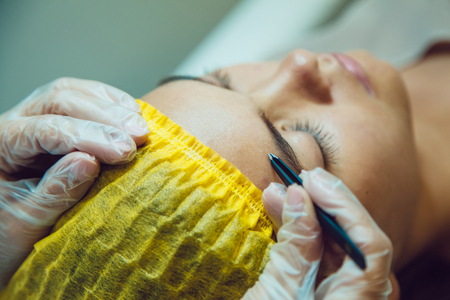 The workflow in a beauty salon girl plucked eyebrows. Tweezers.
