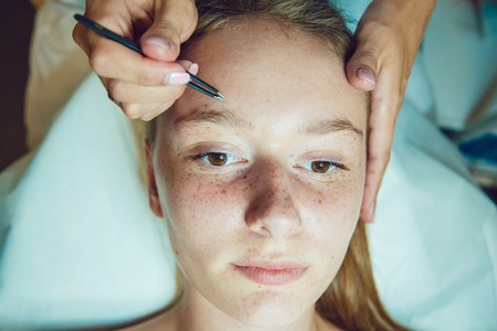 The workflow in a beauty salon girl plucked eyebrows. Tweezers.の写真素材