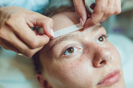 Beautiful young woman getting a face treatment at beauty salon. Adhesive plaster