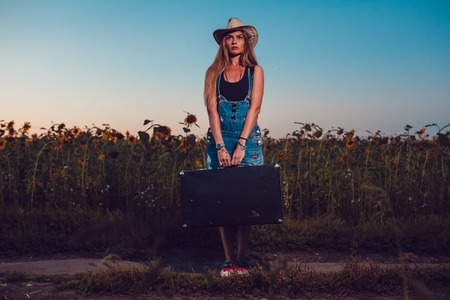 Young woman with retro suitcase traveling in countryside, summer nature outdoorの写真素材