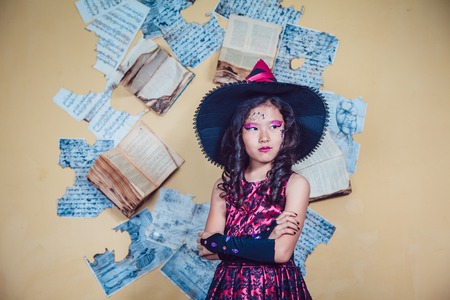 Girl in witch costume standing on the background of yellow wallの写真素材