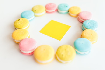 French macaroons laid out in a circle shape on white background with a yellow sticker insideの写真素材