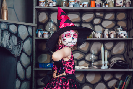 Girl in witch costume and makeup on her face standing in halloween decorationsの写真素材