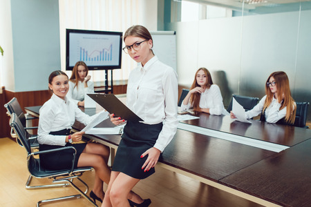 Beautiful business woman on the team's background with documents in handの写真素材