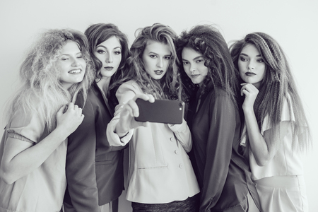 Fashion girls in bright clothes. Beautiful women with professional makeup and crazy hair style, over white background.の写真素材