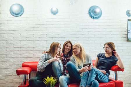 Beautiful girls sitting on the couch, have fun and make selfie Hostelの写真素材