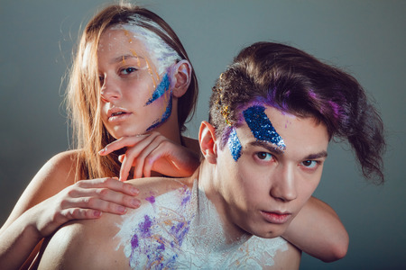 Fashion young man and woman with creative face art on grey background.の写真素材